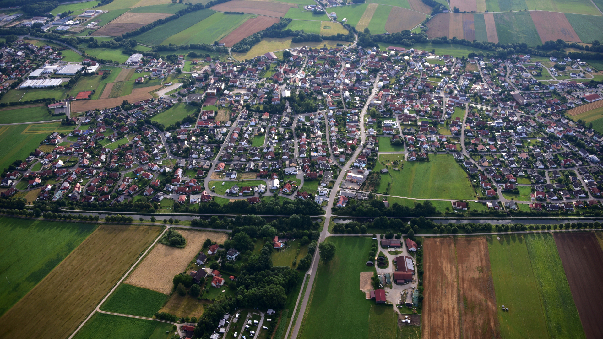 Luftaufnahme einer bayerischen Ortschaft mit Feldern und Wald
